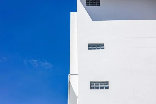 A bright, minimal building facade below a clear blue sky